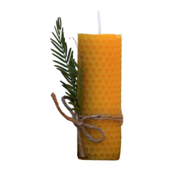 Handcrafted yellow beeswax candle with honeycomb texture, decorated with a green sprig and twine.