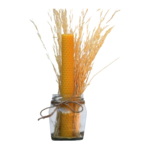 Yellow beeswax honeycomb candle in a glass jar tied with twine and decorated with dried grass.